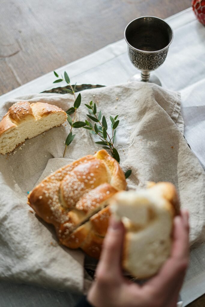 Close-up of a Shabbat table setting featuring challah bread and a kiddush cup indoors.